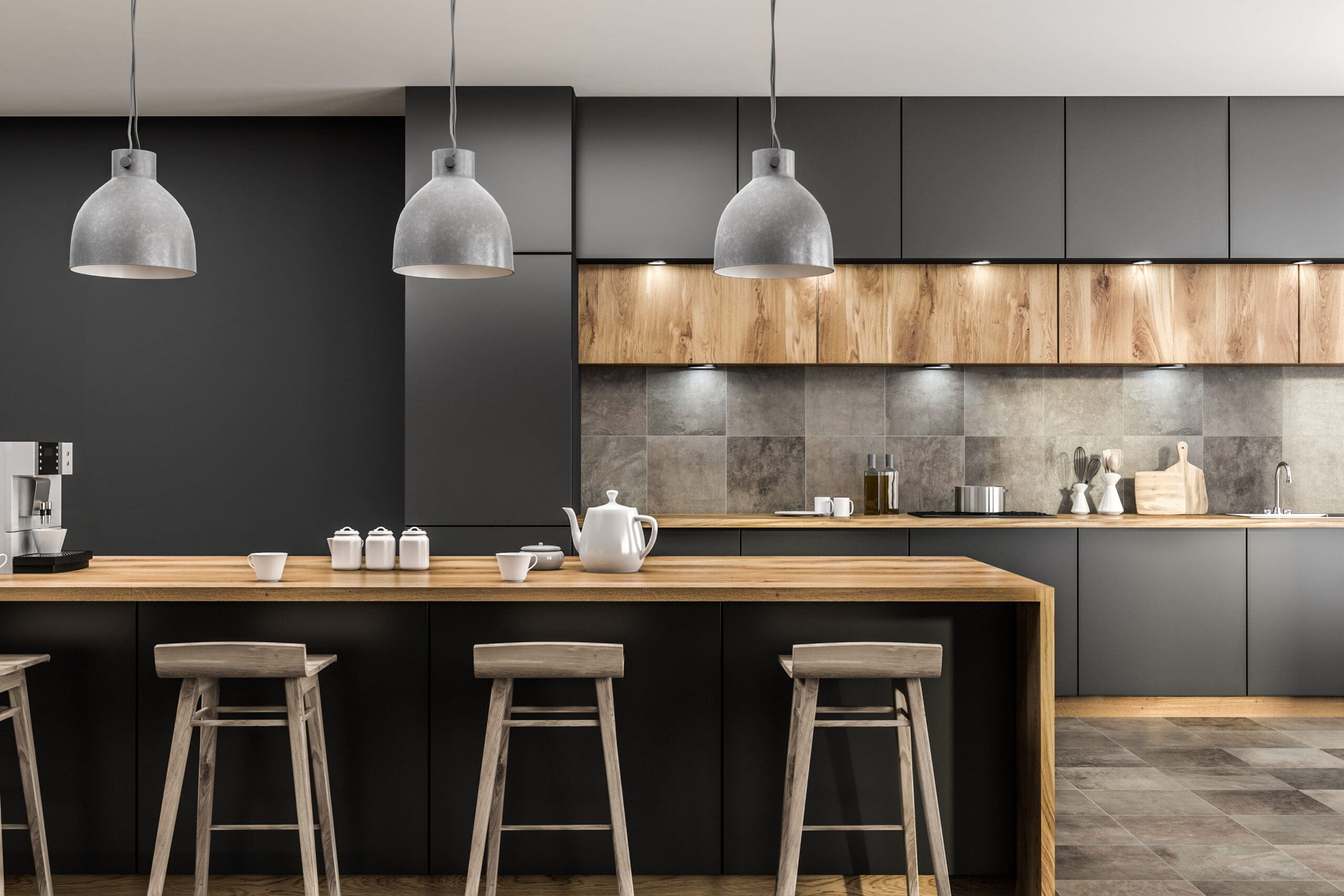 A modern kitchen with a large wooden island, four wooden stools, and three gray pendant lights. The background features dark cabinets, wooden upper cabinets, and a tiled backsplash. Kitchenware and a teapot are on the island.